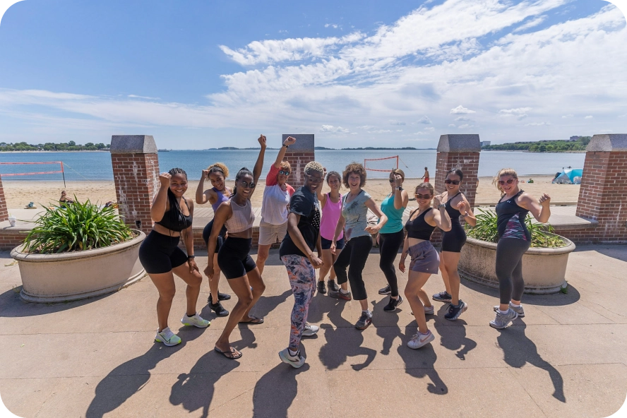 Group of women posing for a picture while exercising on the waterfront